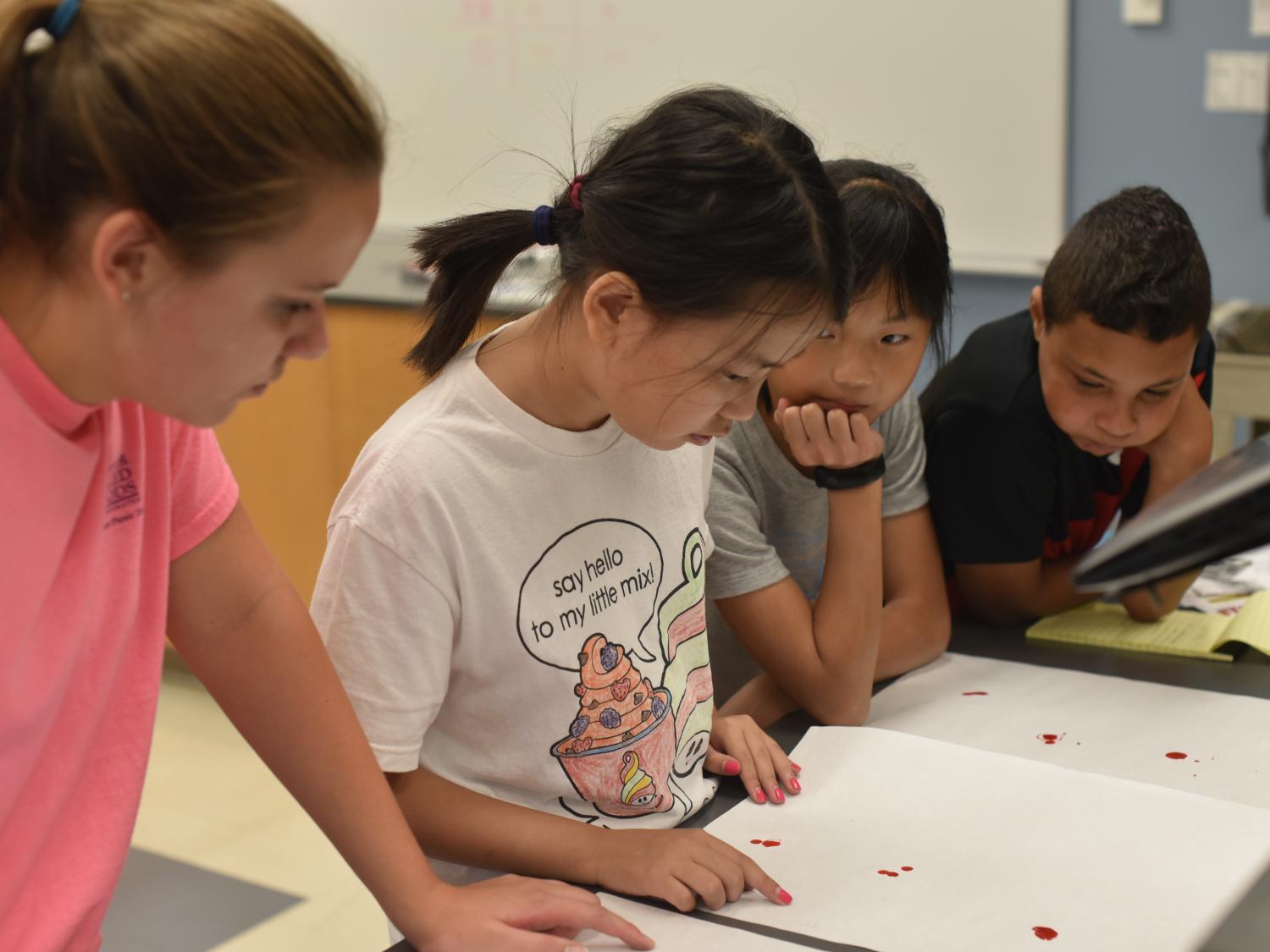 Morgan Farrell, far left, and her classmates examine red dye they recovered from a mock crime scene during Penn State Behrend's "CSI-Crime Scene Investigations" College for Kids course.