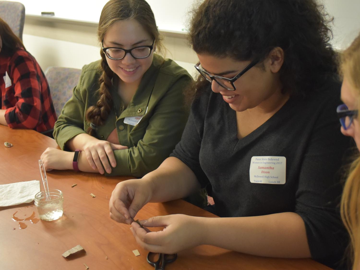 McDowell High School student Samantha Dixon, center, attempts to get her five-cent battery to conduct. 