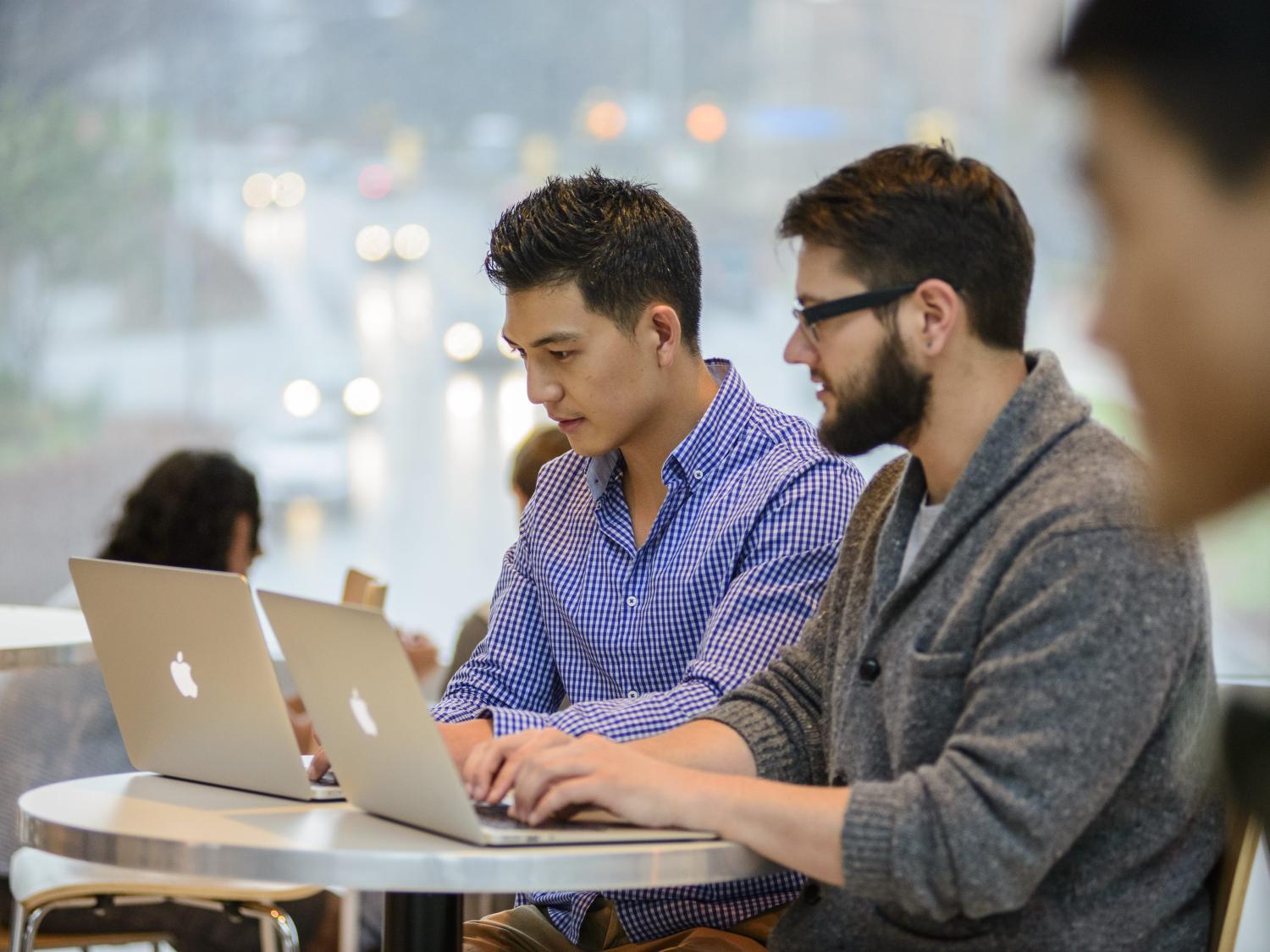 Two Penn State alumni work on computers.