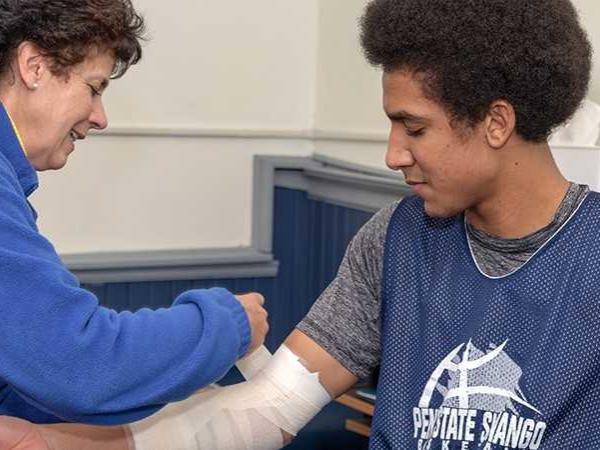A woman wraps an athletes arm.
