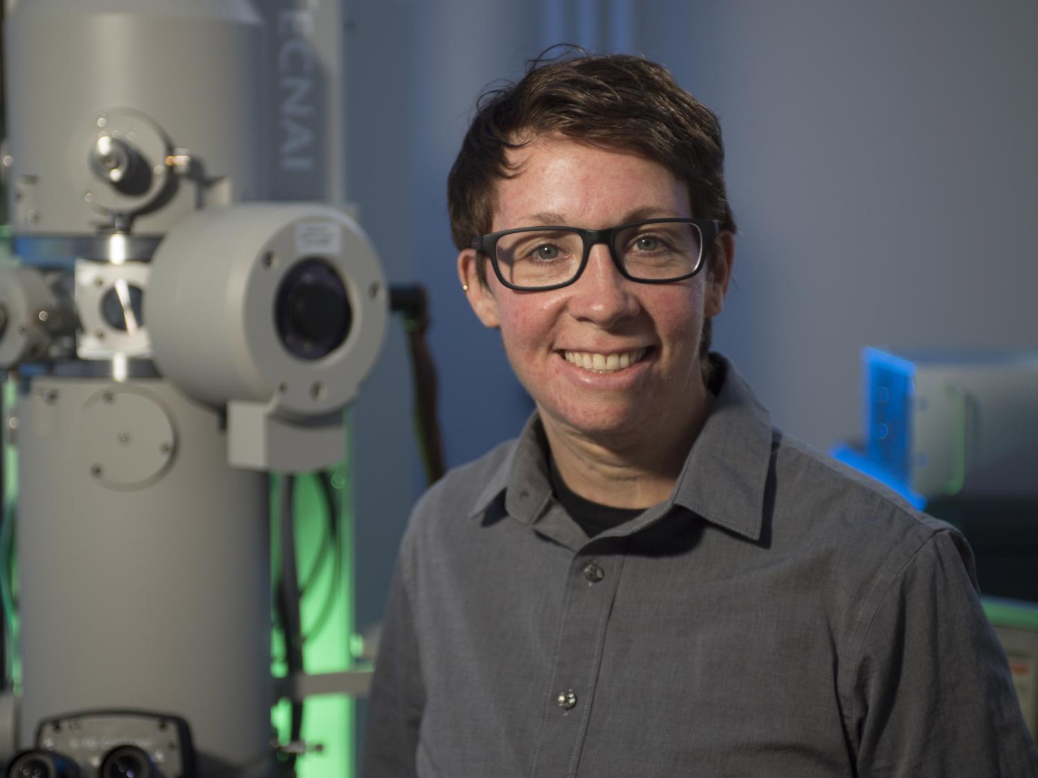 A woman sits in front of an electron microscope
