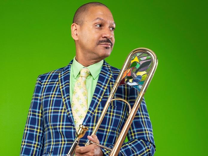 A man holds a trombone and looks to his left.