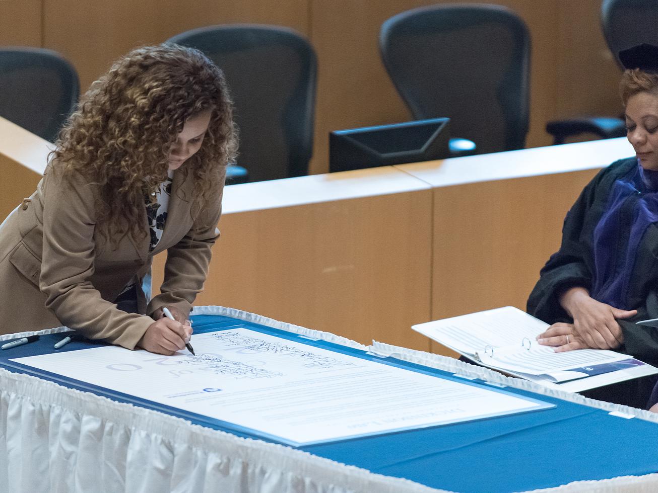 First-year Dickinson Law student Giovanna Brackbill signs the Statement on Professionalism during convocation on September 22
