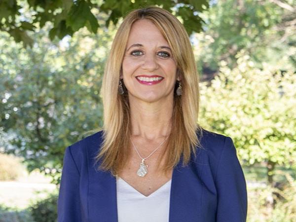A female faculty member standing outside by a tree