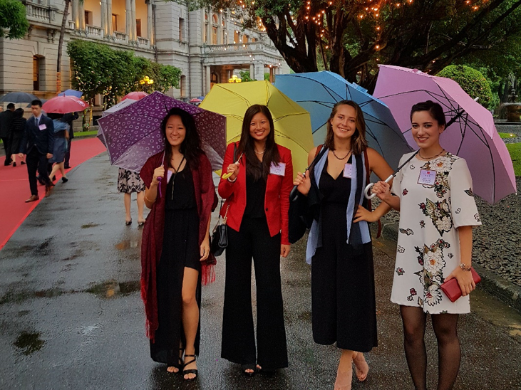 Four women stand with colorful umbrellas