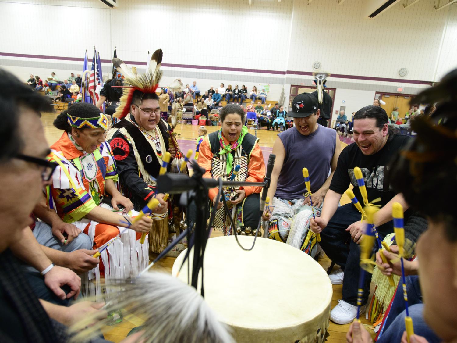 Traditional American Indian drummers sit around a drum and play a traditional song 