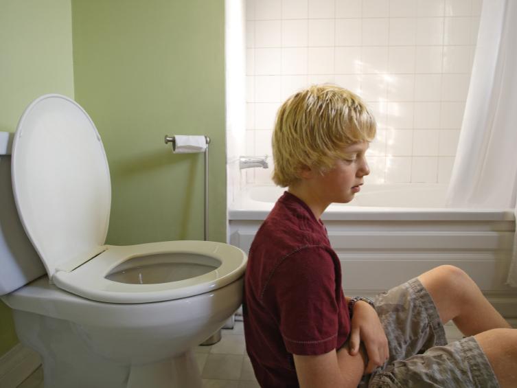 boy sitting in front of toilet