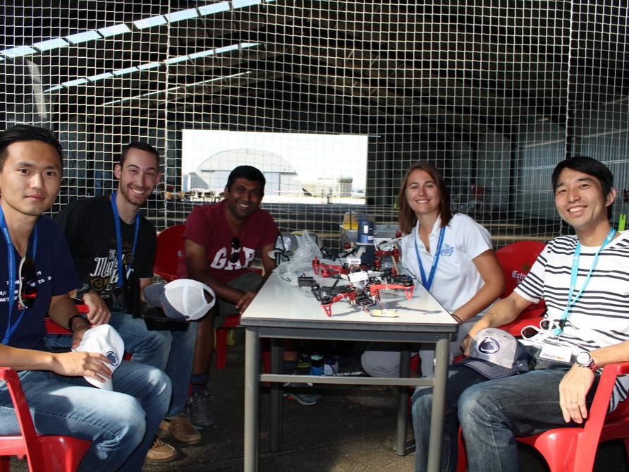 Four men and a women sit around a table with drones on it.