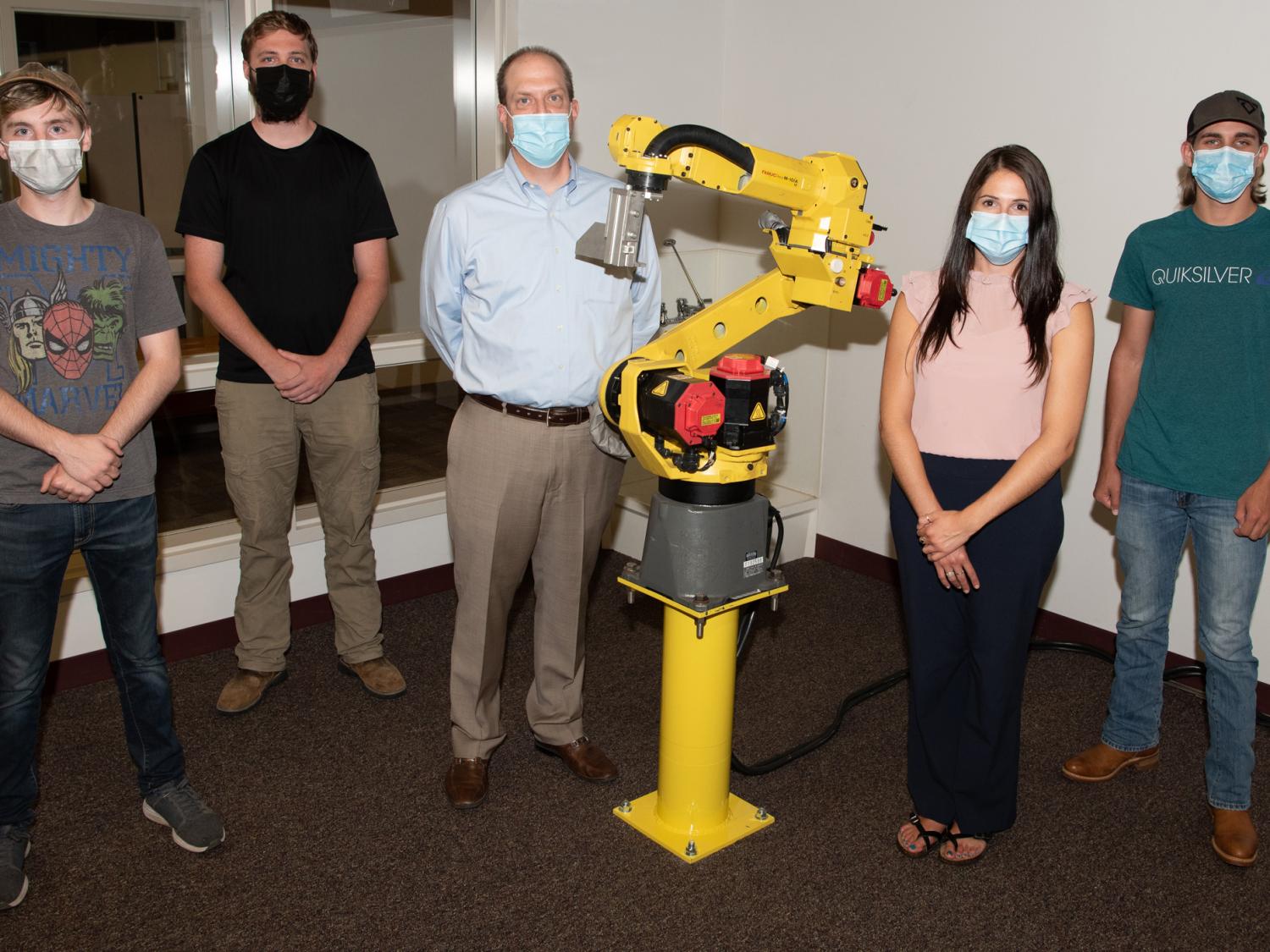 An engineering robot with five people standing behind it