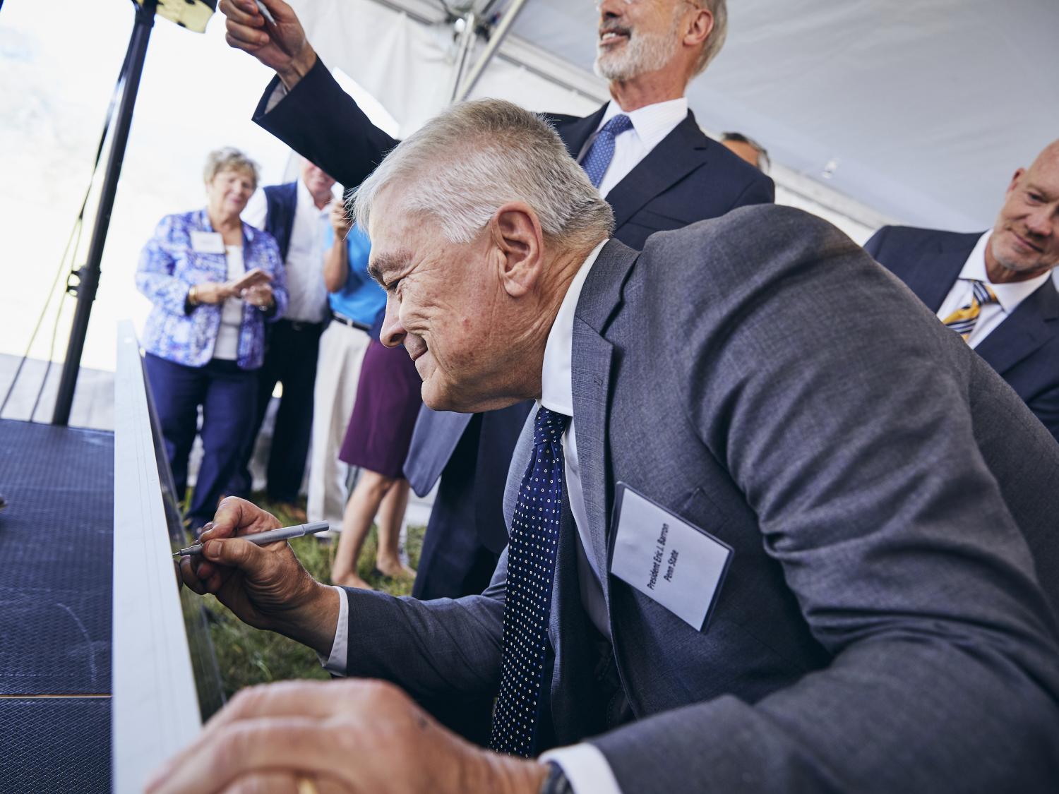 Penn State President Eric J. Barron signs a solar panel at the groundbreaking for a utility-scale solar project in Franklin County on Sept. 6, 2019.