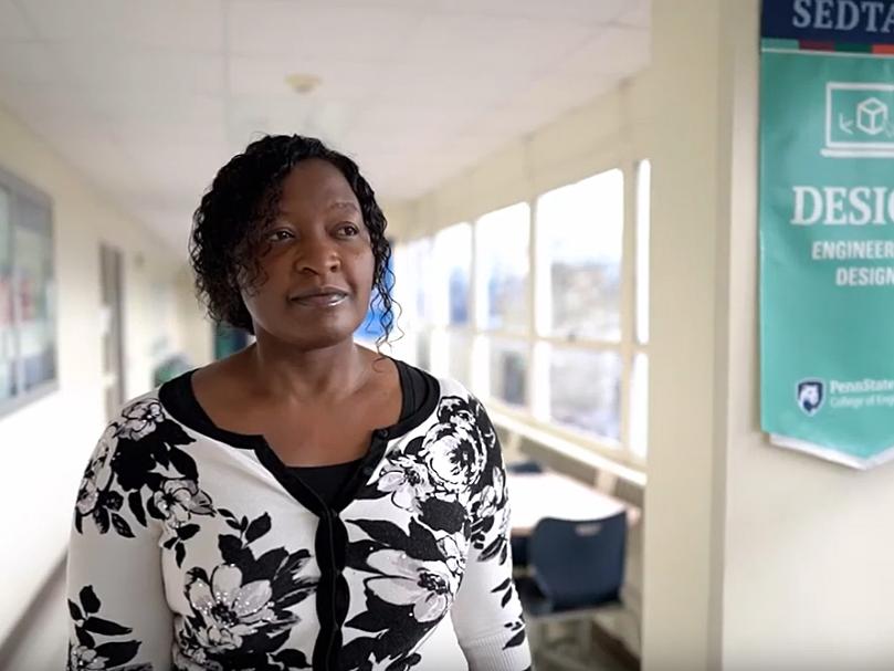 Esther Obonyo walking down a brightly lit hallway