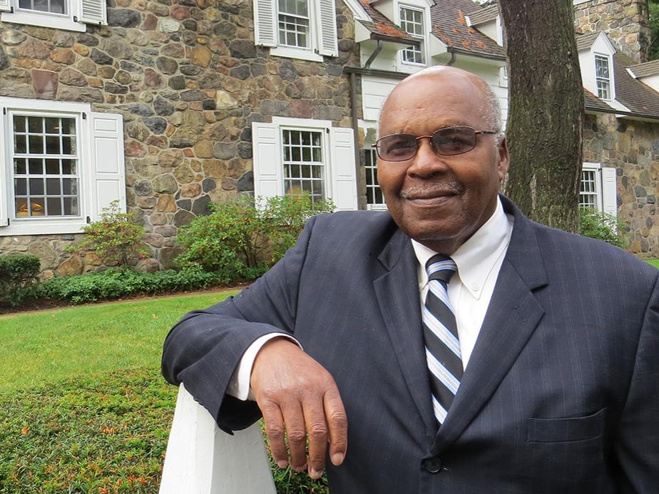 Retired Penn State Behrend faculty member Eva Tucker Jr. stands in front of Glenhill Farmhouse.
