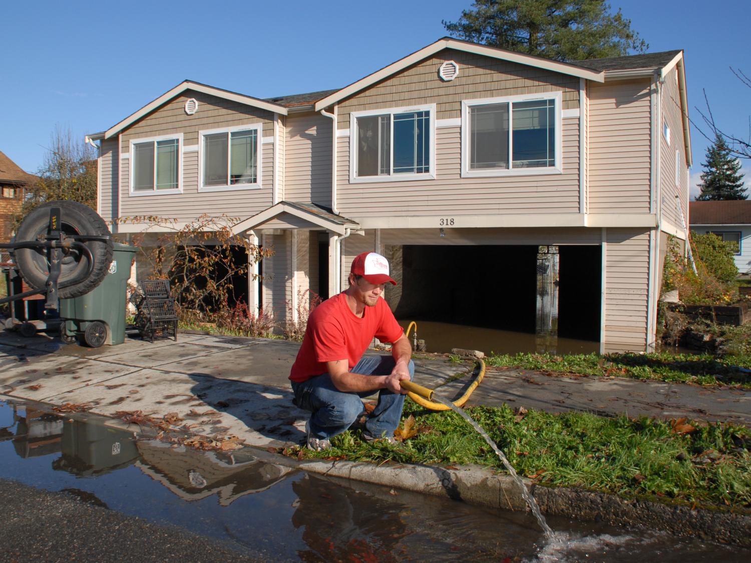 Large two story house with man pumping water out of the basement and lower level