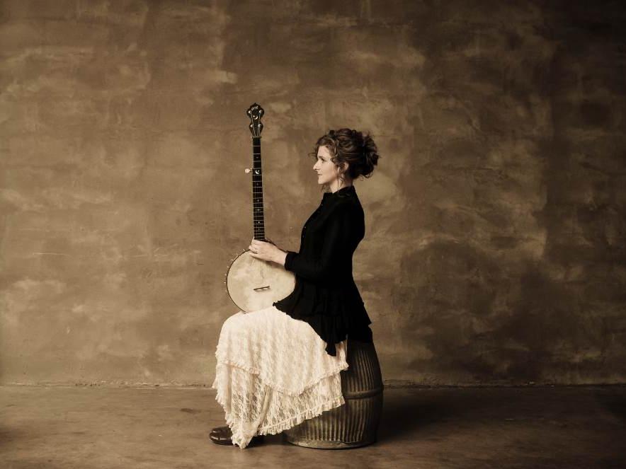 Musician Abigail Washburn sits on a stool with her banjo in hand.