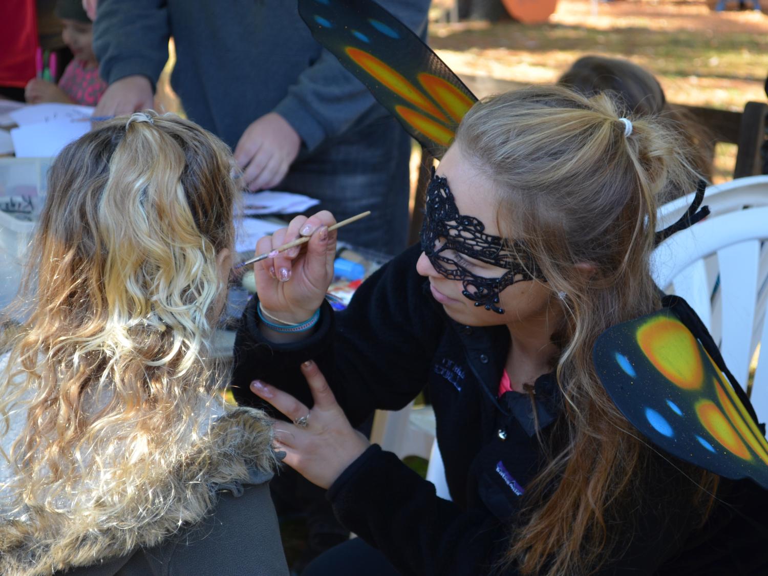 Volunteer in mask paints child's face