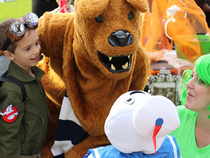Trick-or-Treaters getting their photo taken with the lion at Fall Fest.