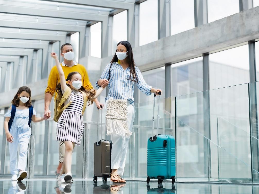 Family walking through airport with their luggage.