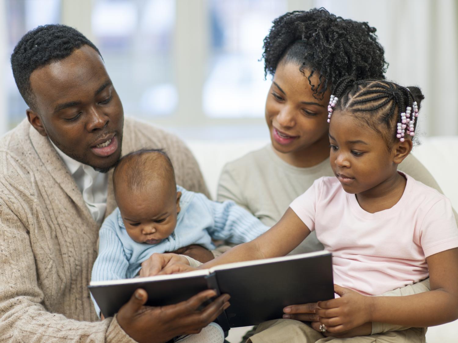 African American family reading to their young children.