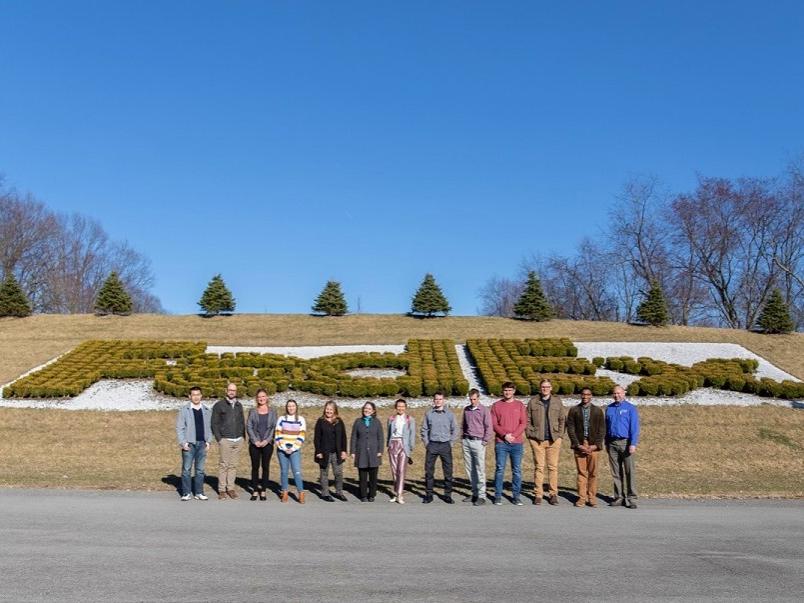 Group stands in front of bushes that spell out FedEx