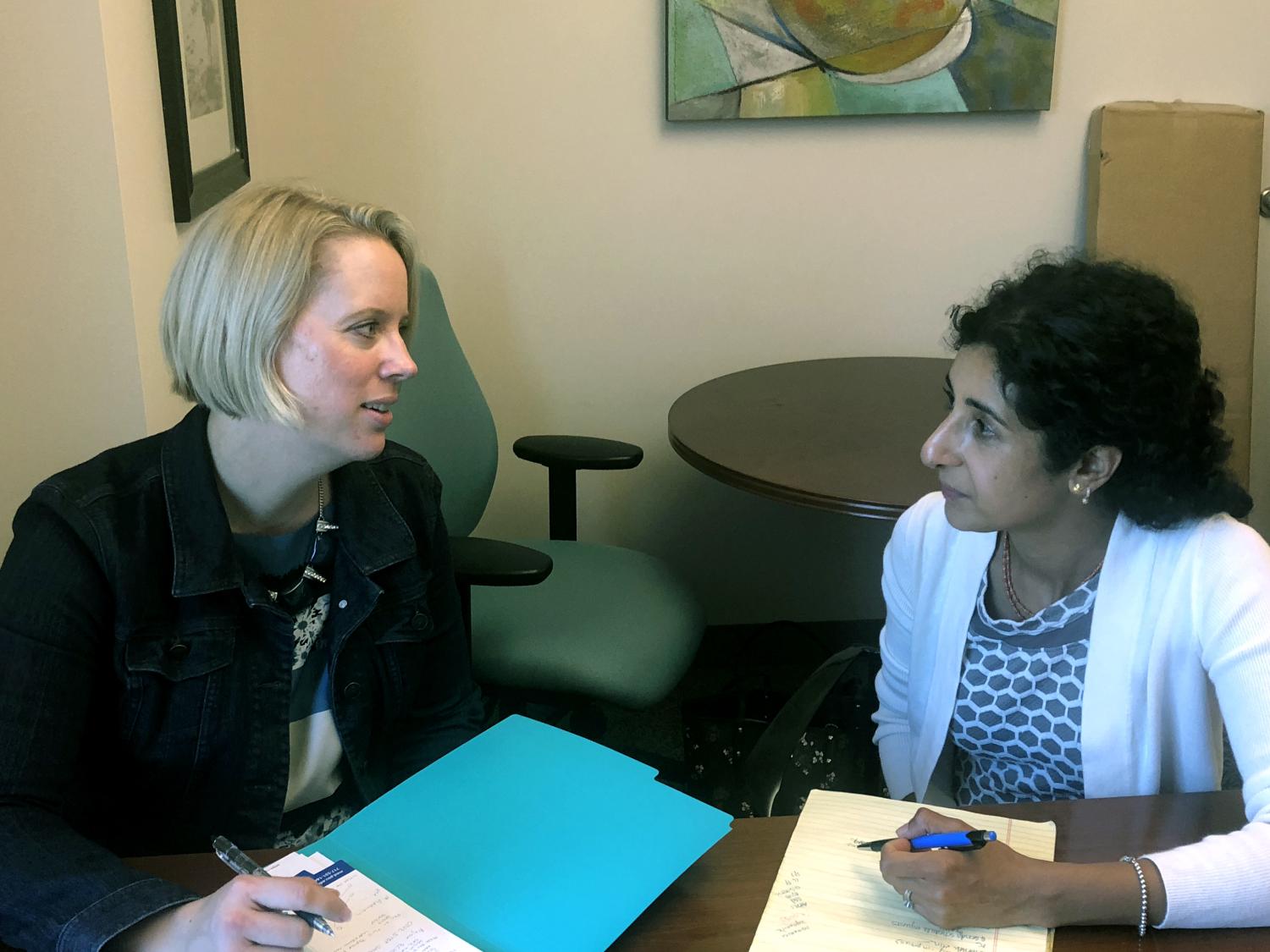 Two women sit and talk at a desk