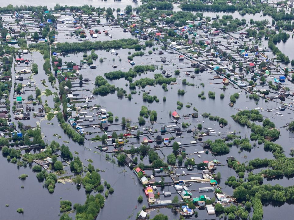 Tops of houses and trees peek through the waters of a flooded river
