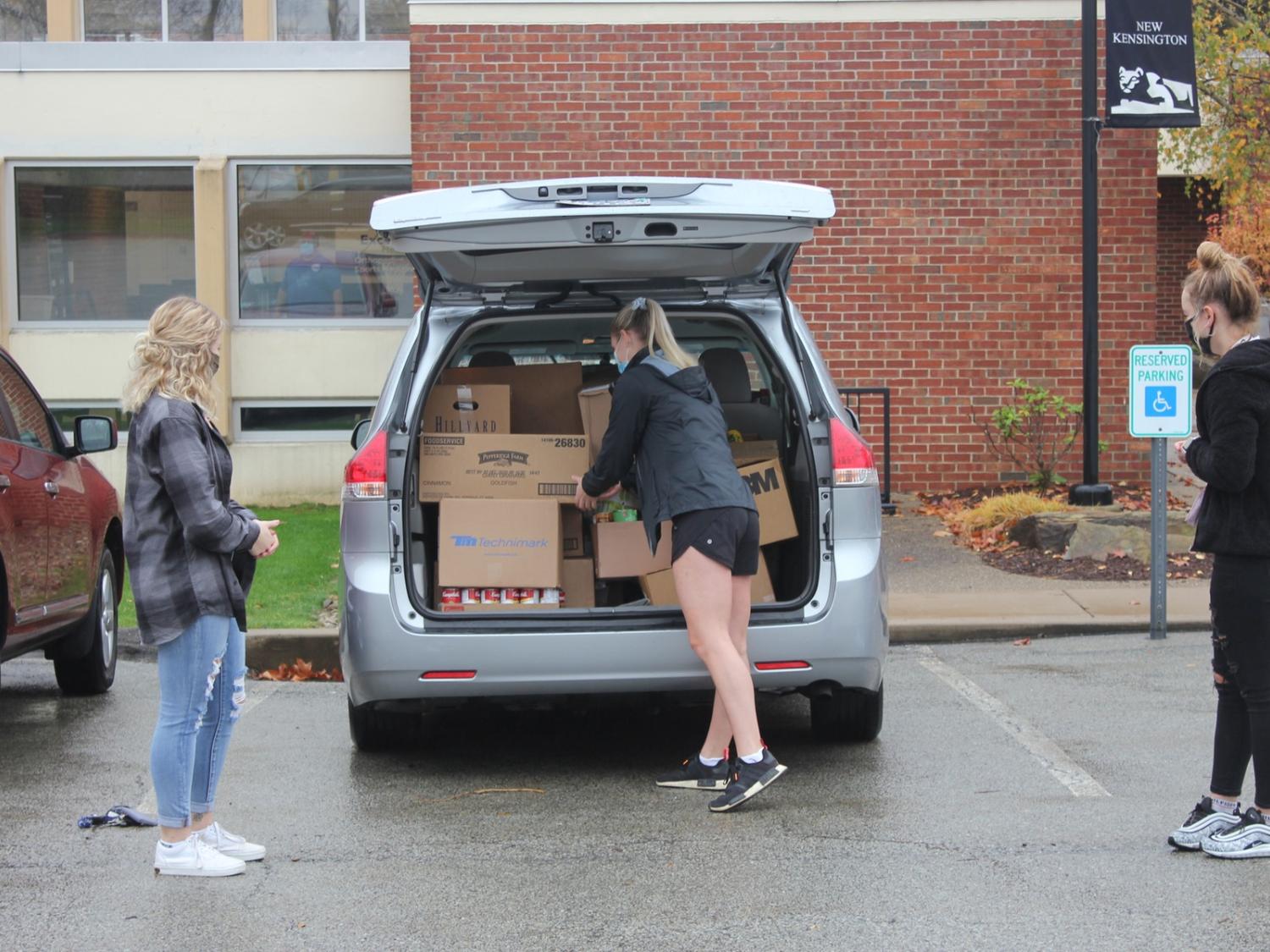 Student loads food donations into car