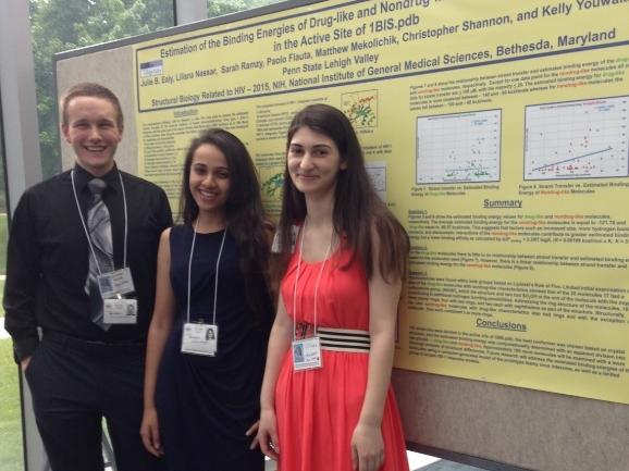 Three students pose in front of research poster