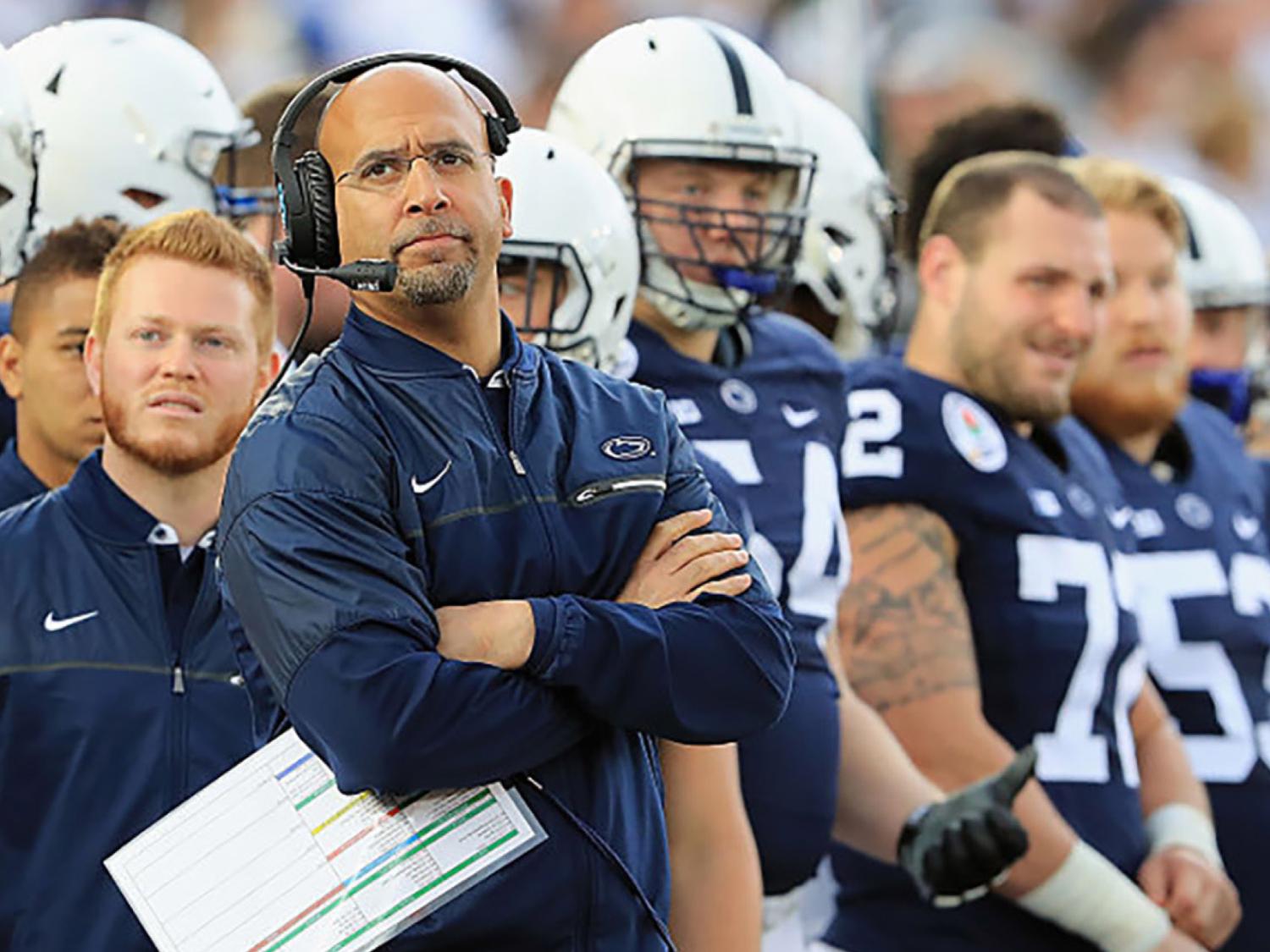 Coach Franklin standing on sidelines looking up with headset on