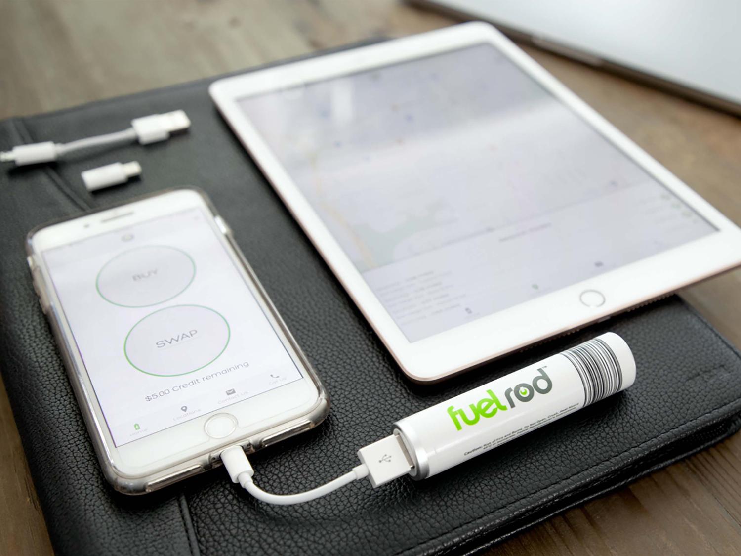 An iphone and tablet laying on a black padfolio. The iphone is plugged into a FuelRod charging device
