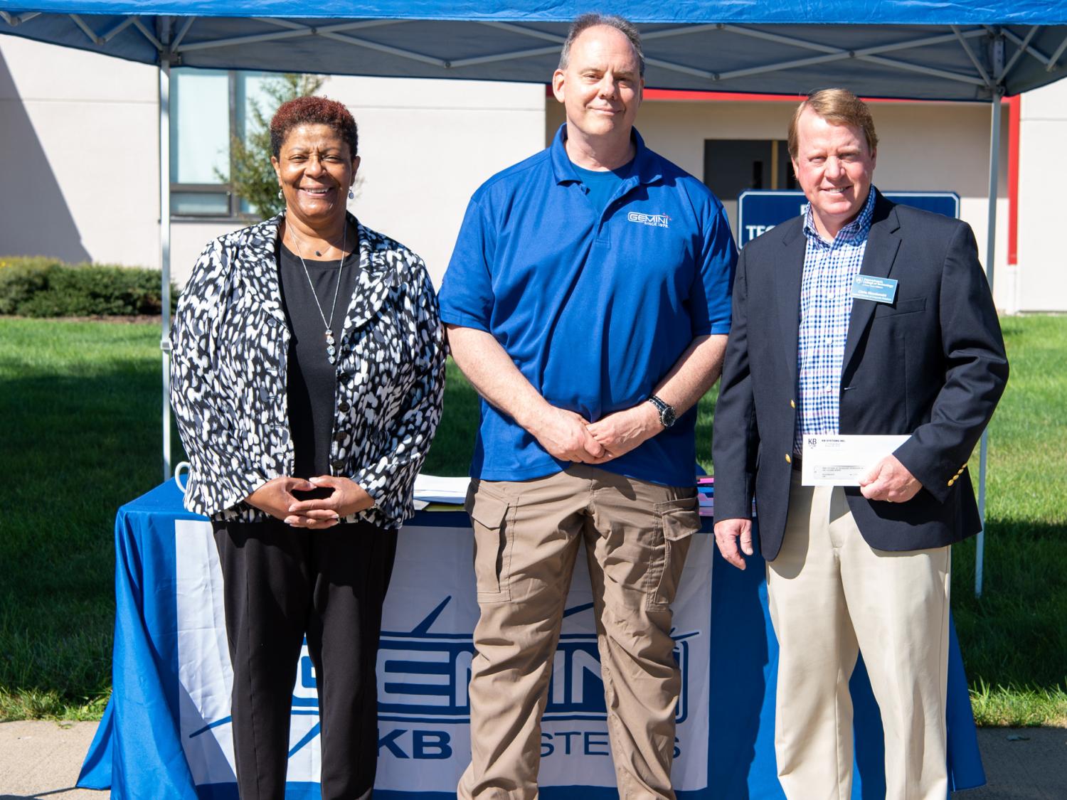 Three people stand together in a row