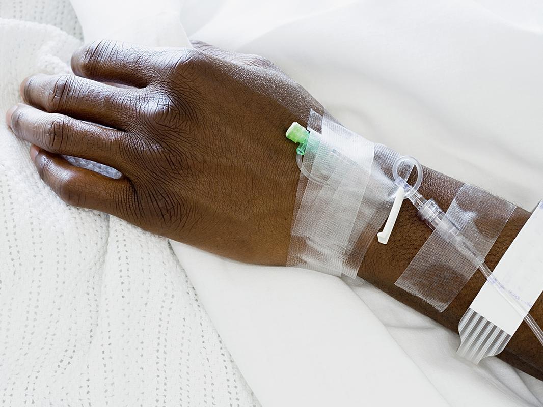 An image of a hand of a Black patient in the hospital receiving intravenous fluids. 