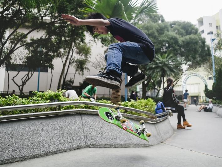 A boy does a skateboard trick in a Hong Kong park.