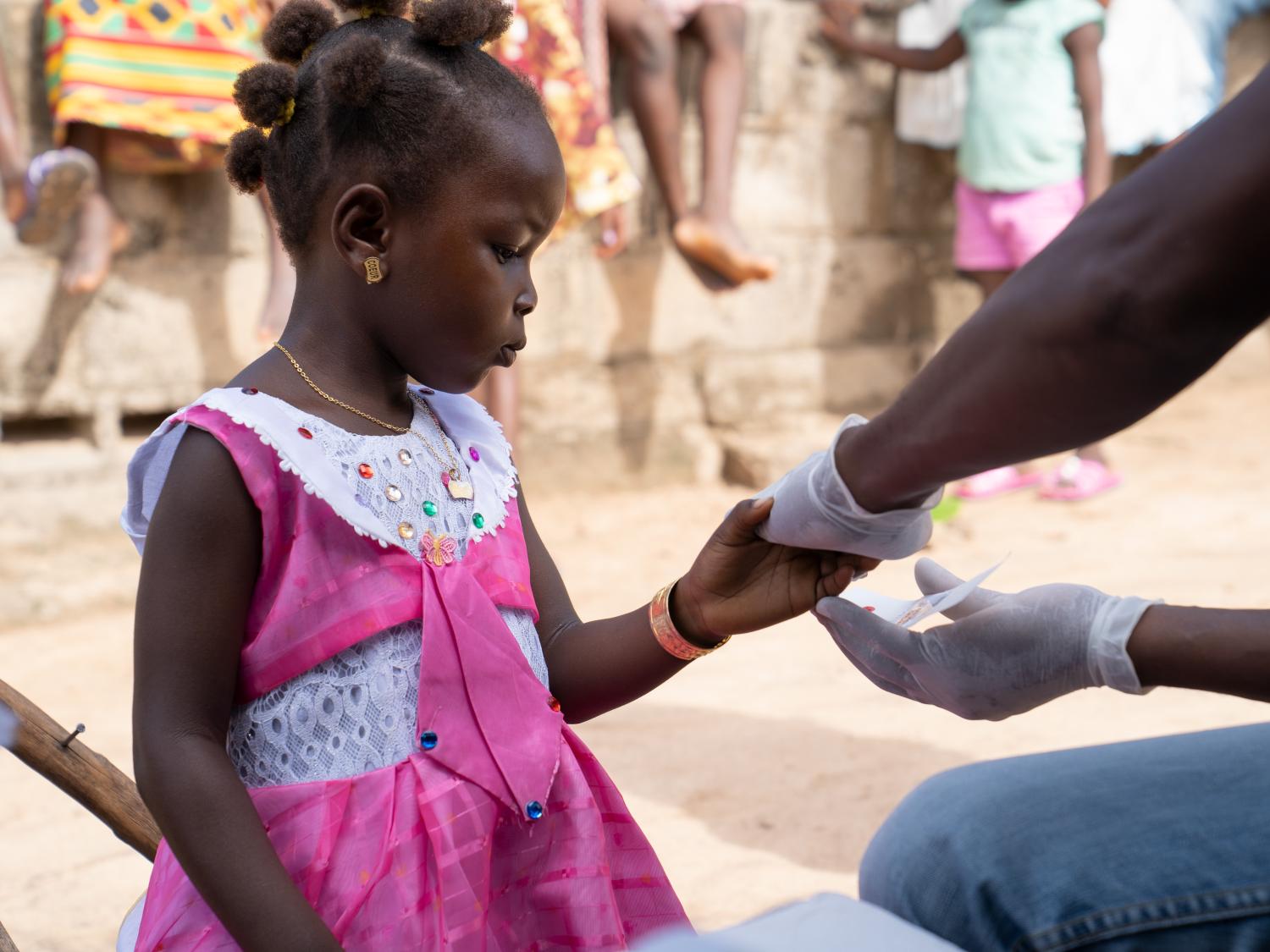Girl getting finger prick test for malaria