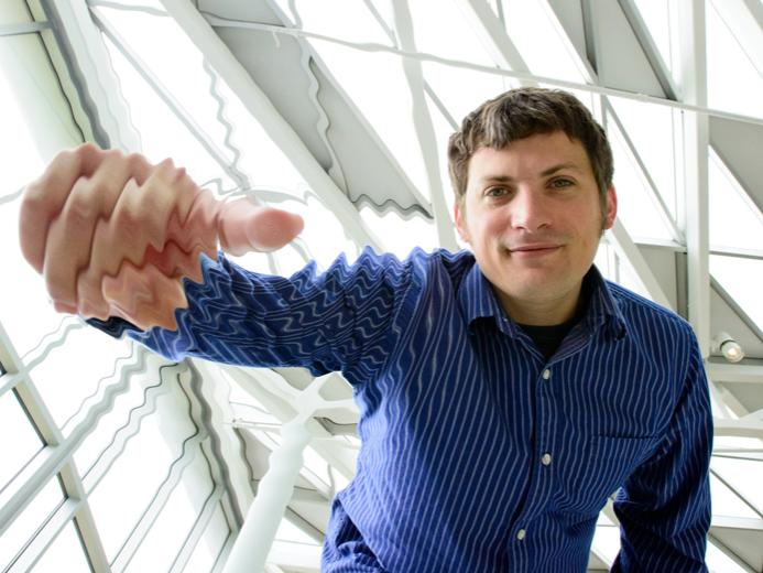 Chad Hanna, an assistant professor of physics at Penn State makes rippling waves seem to appear in a photograph of himself