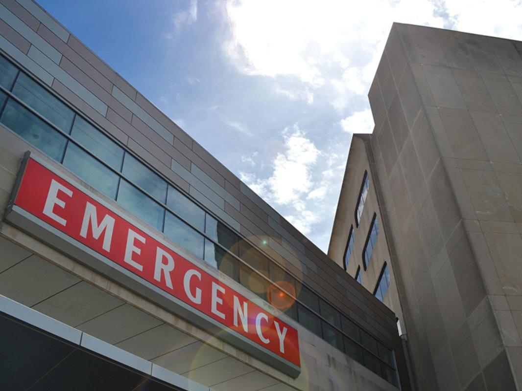 A view from below of a building bearing a red sign with the word “EMERGENCY” prominently displayed.
