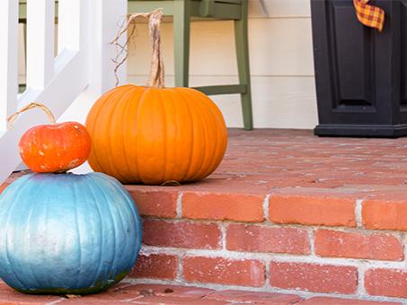 Two orange pumpkins and one teal pumpkin on steps