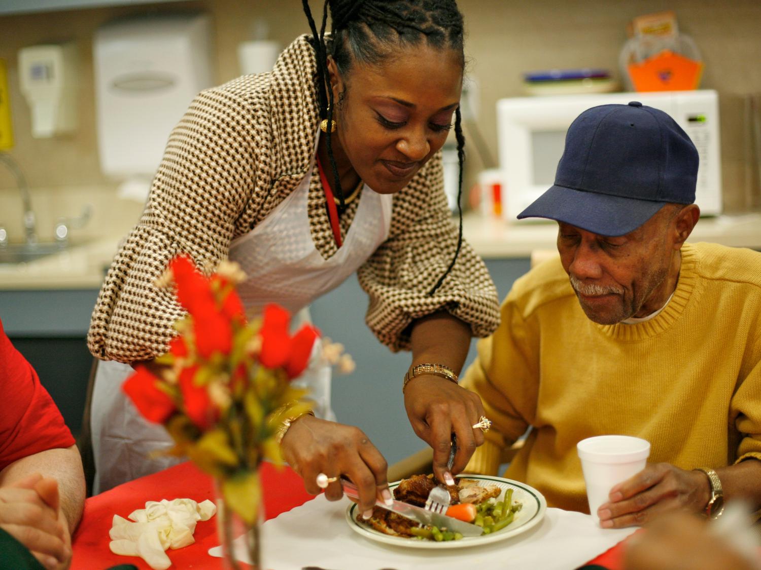 A geriatric caregiver helps an older adult.