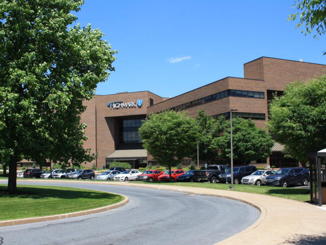An external photo of the Highmark building in East Pennsboro Township. Trees, a bus shelter and driveway are in the foreground.