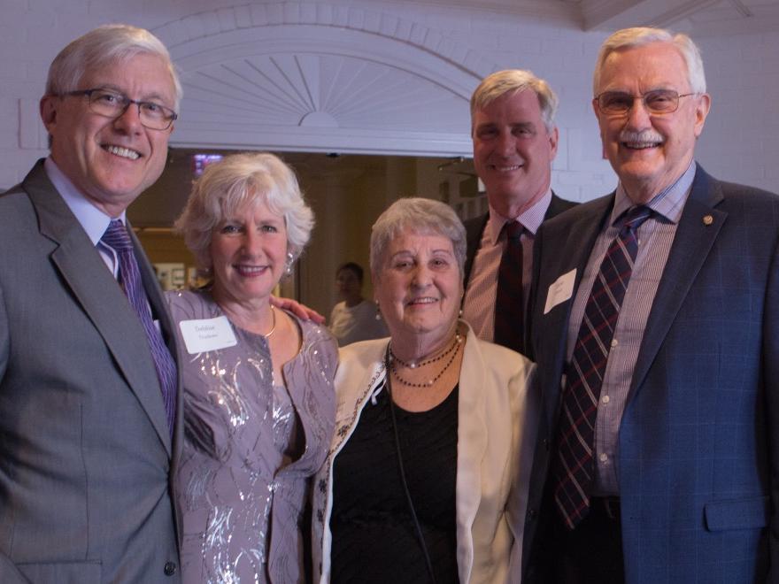 A group of people dressed in formal wear smile for the camera.