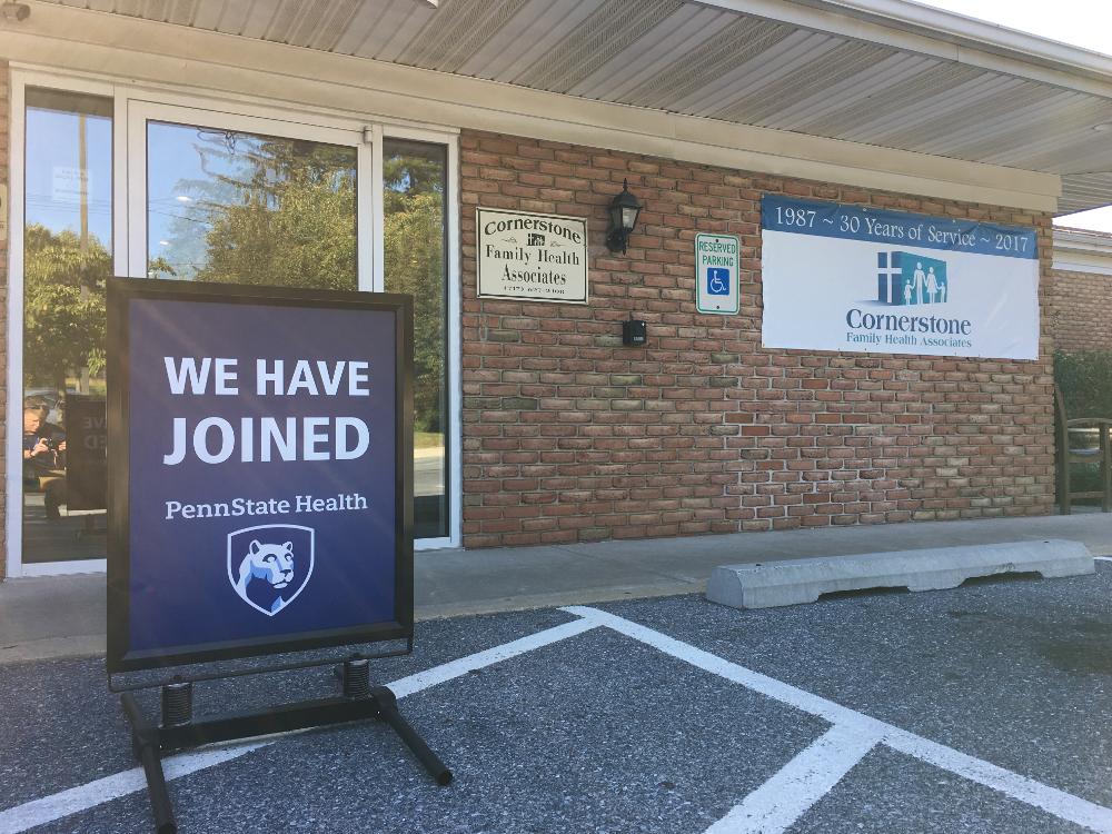 A sign reading "We have joined Penn State Health" sits in front of a brick building labeled "Cornerstone Family Health Associates."