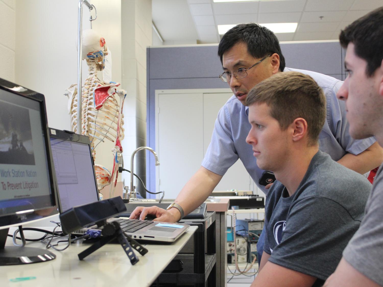 Ling Rothrock helps a student design team initialize the eye-tracking software that tests the effectiveness of the students' game