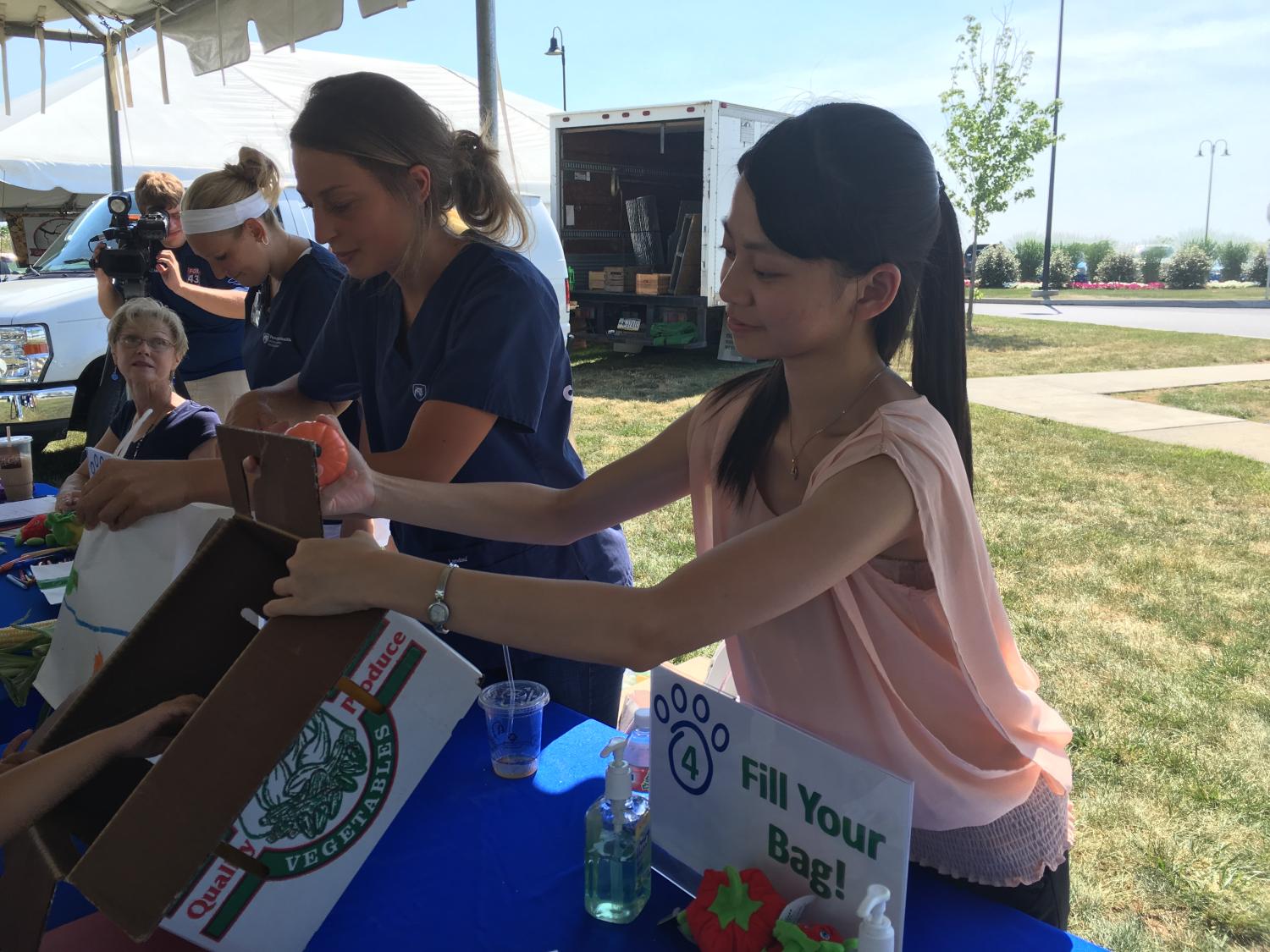 Two students from the International Health Exchange Program work at the Farmers' Market in Hershey.