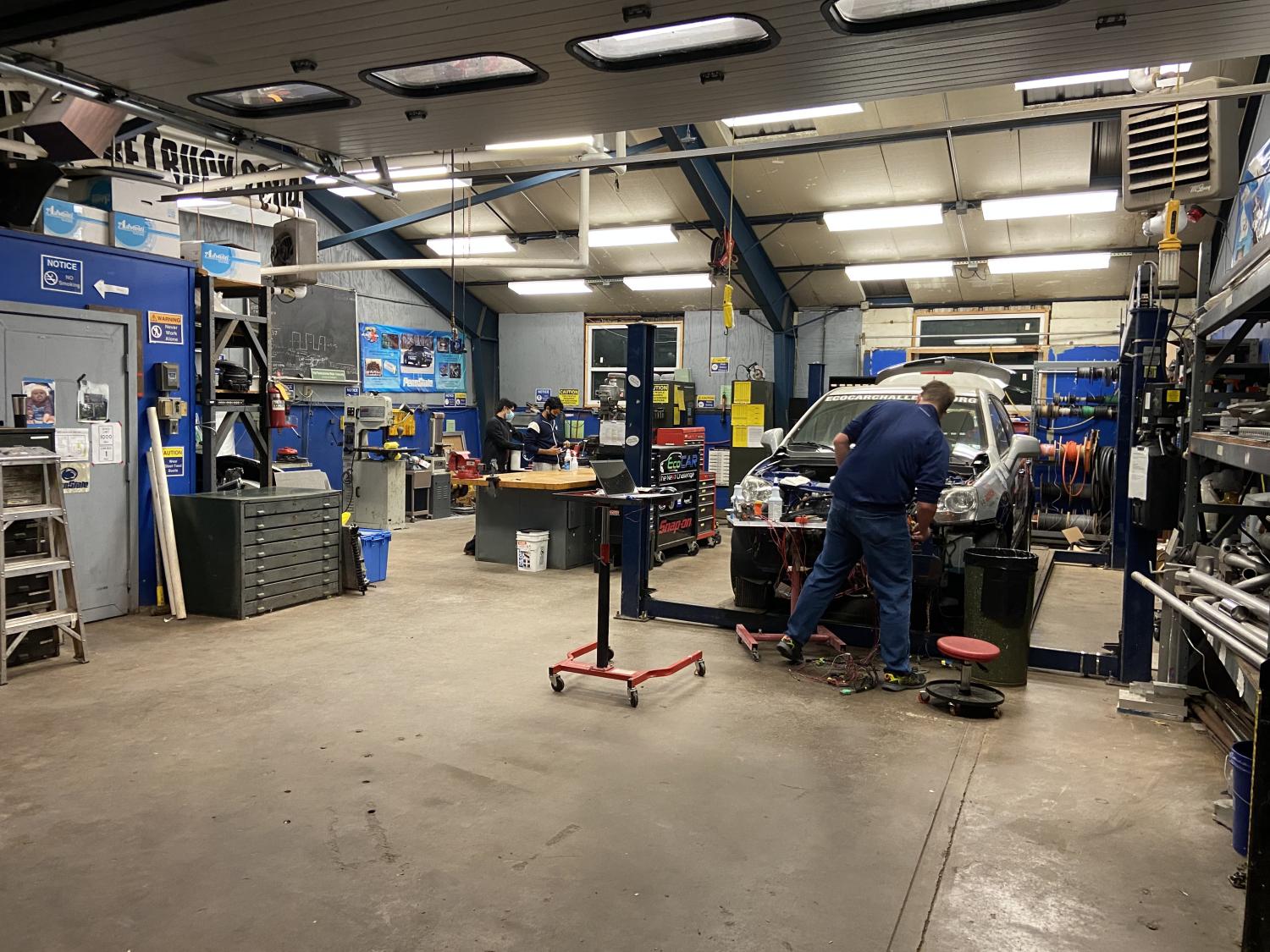 Several students work on cars in an autoshop. 