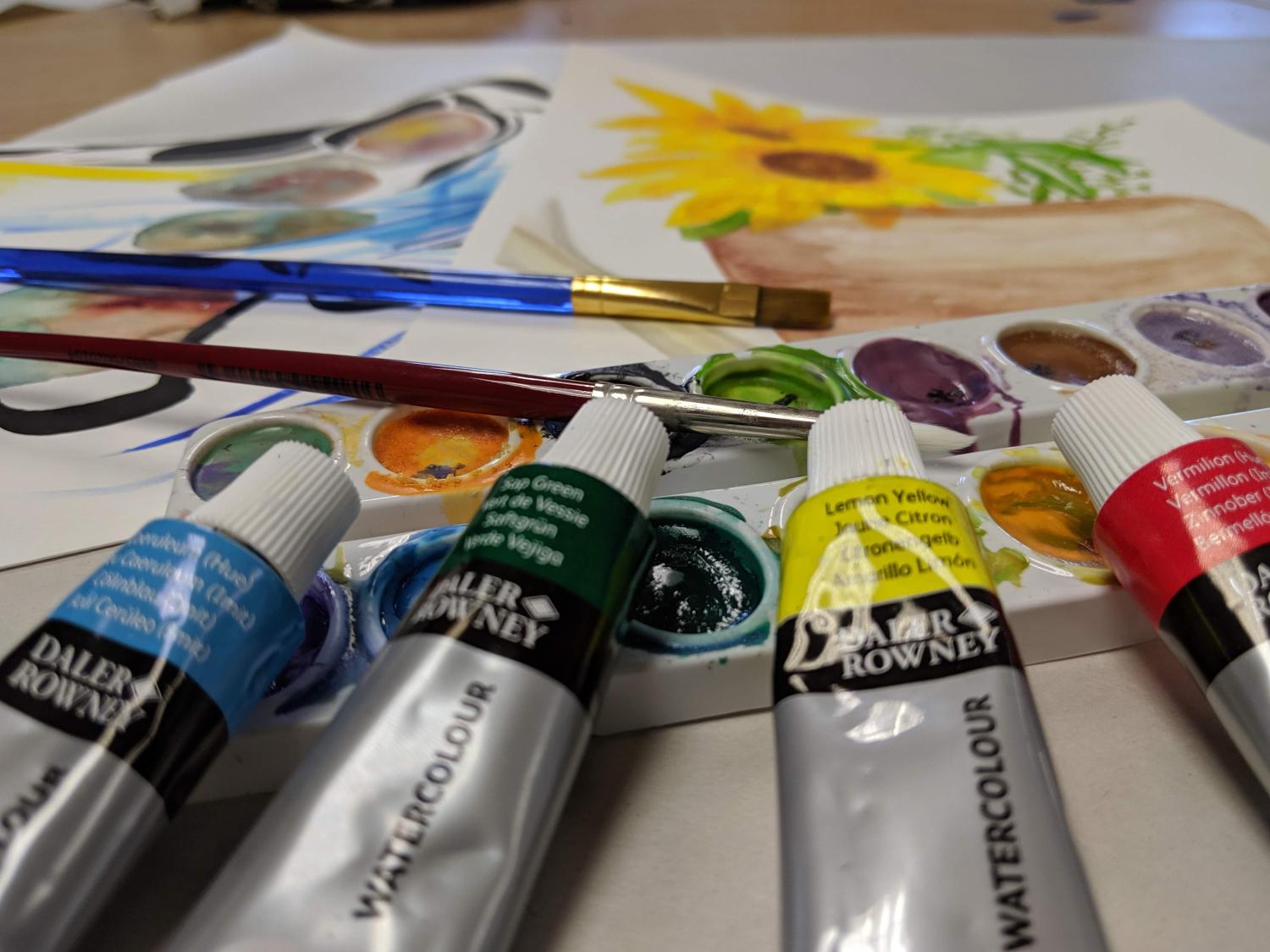 Colorful oil paints and brushes next to a canvas