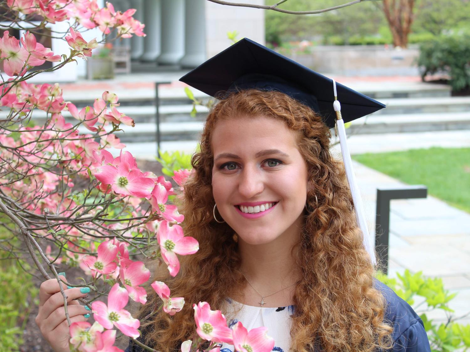 Bailyn Bench in graduation cap next to flowering tree