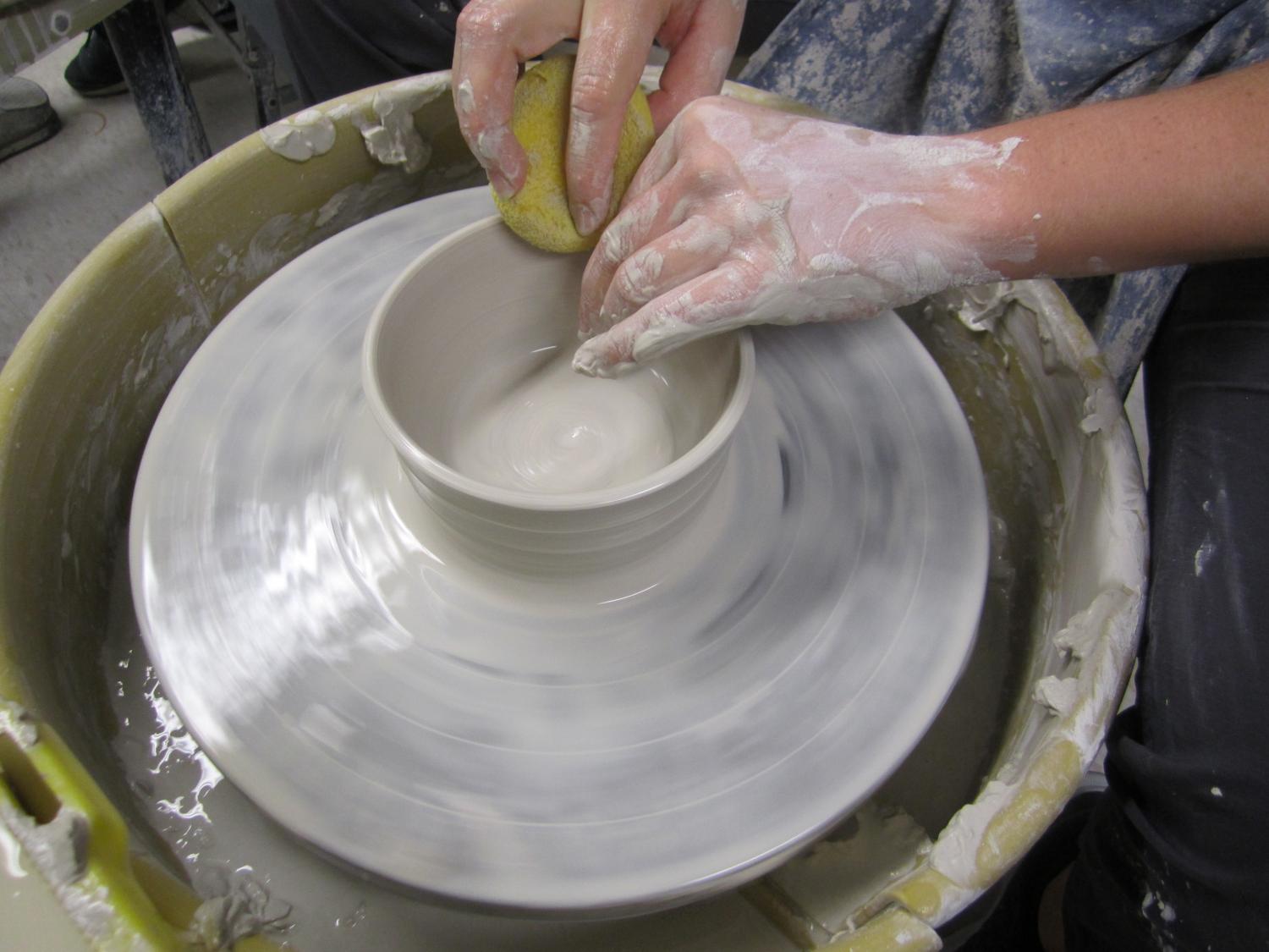 hands forming a bowl on a pottery wheel