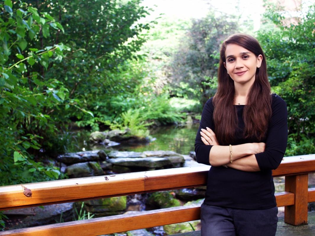 Woman standing on bridge above a pond