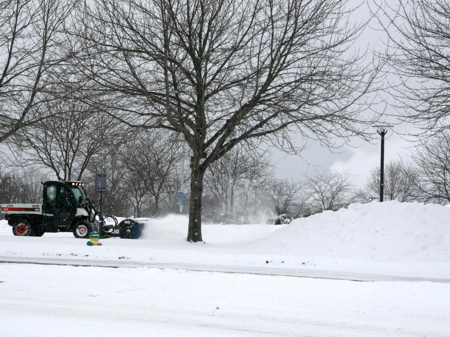 A worker drives a snow brush to clear sidewalks.