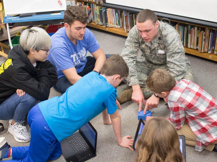 Mechanical engineering students Xueqi Wang, Colton Layhue, and Jordan Sterner work with elementary students.