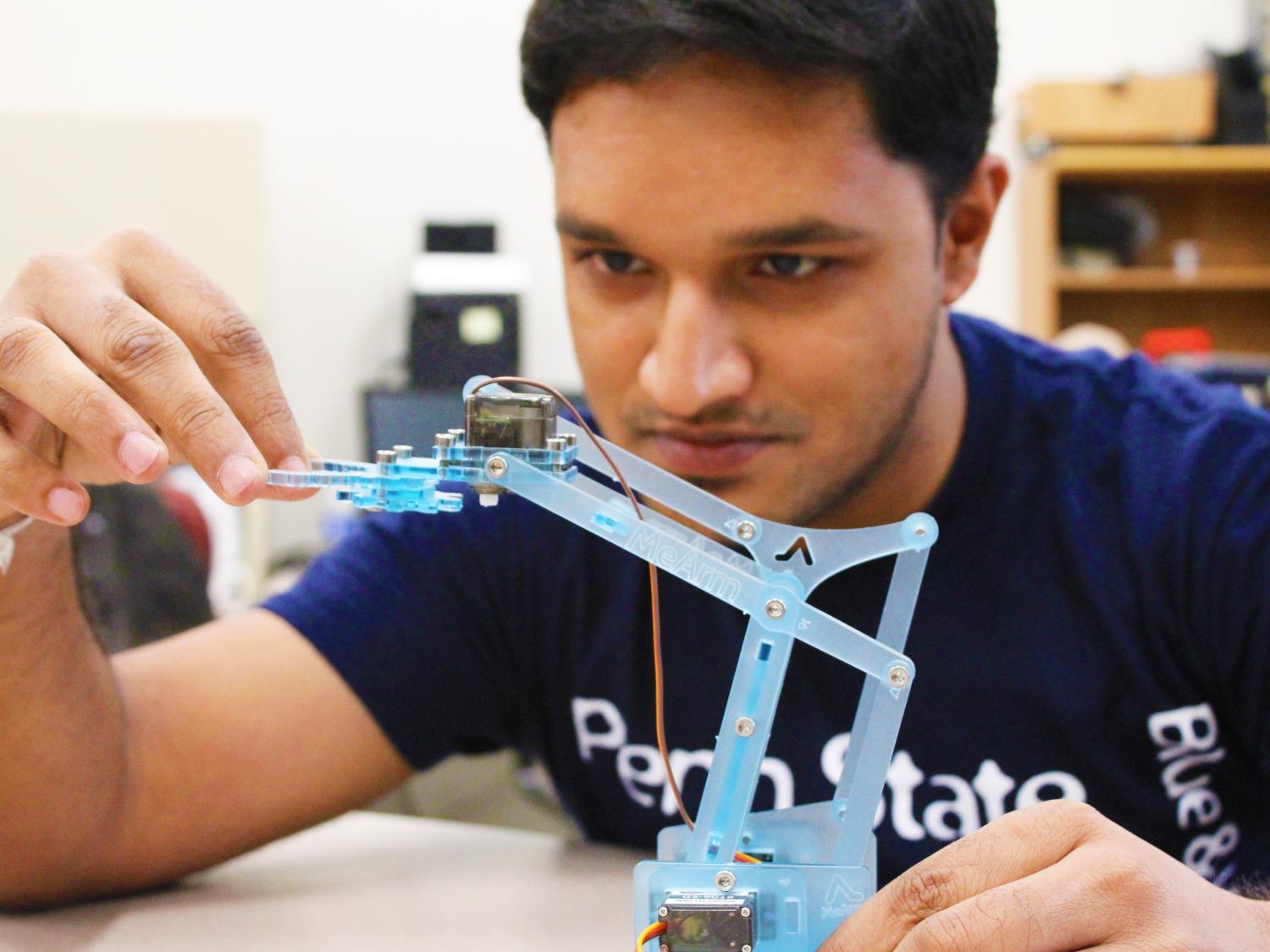 Rakshith Badarinath inspects the robotic arm he built